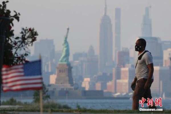 资料图：当地时间7月4日，一位居民戴着口罩从纽约曼哈顿对岸的海滨走过。当日是美国独立日，美国多地疫情仍面临严峻形势。
<a target='_blank' href='http://www.chinanews.com/'>中新社</a>记者 廖攀 摄