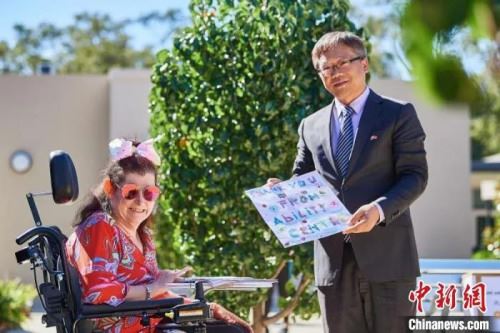 　资料图：当地时间5月，孙晓轩接受残疾人服务中心居民代表Anita Jambanis 回赠画作。　Daniel Carson　摄